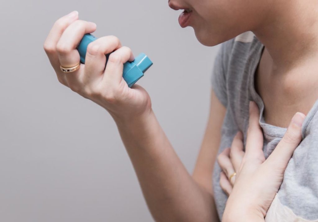 woman-holding-inhaler - what happens during asthma attacks